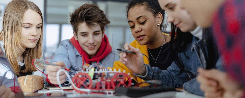 Gruppe von Schülerninnen und Schülern, die elektrisches Spielzeug und Roboter im Robotik-Klassenzimmer bauen und programmieren