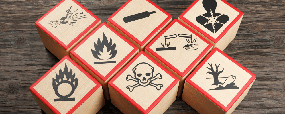 Holzklötze mit verschiedenen Symbolen chemischer Gefahrenwarnungen auf Holztisch