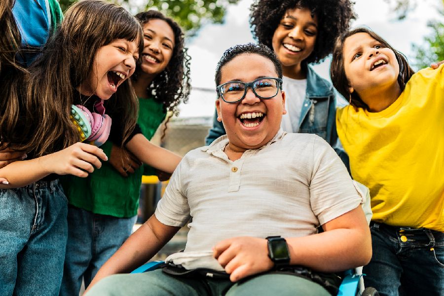 lachende Kinder in einem Kreis. EIn Kind sitzt im Rollstuhl. per Klick gelangen SIe zu der Seite Hinweise für den Umgang mit Behinderung und Beeinträchtgung
