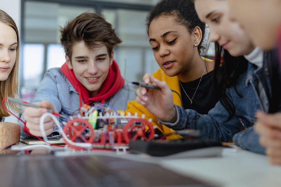 Gruppe von Schülerninnen und Schülern, die elektrisches Spielzeug und Roboter im Robotik-Klassenzimmer bauen und programmieren. Per Klick gelangen Sie zur Seite Fächer (Übersicht)