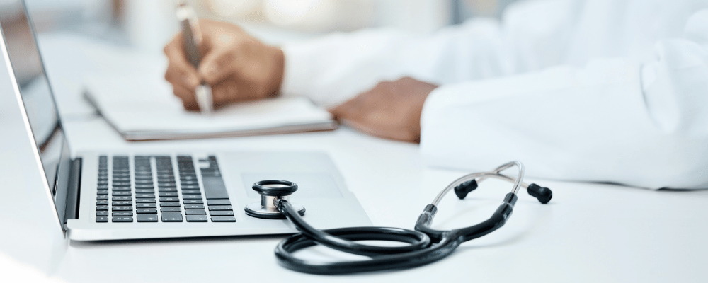 Laptop, Stethoskop und Arzt schreiben im Notizbuch