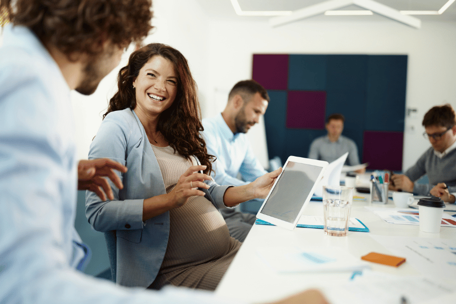Lehrerzimmer. Schwangere Frau sitz lächelnd mit Ihren KollegeInnen zusammen Per Klick gelangen Sie zur Seite Mutterschutz